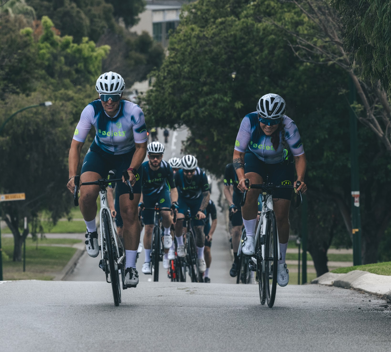 Cyclists in matching uniforms riding on a road with trees in the background
