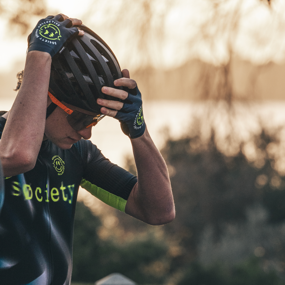 Person wearing a cycling outfit with gloves and helmet, standing outdoors.