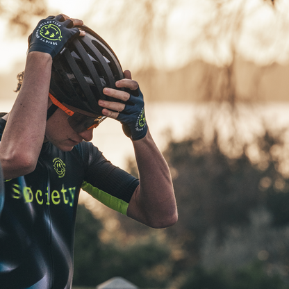 Person wearing a cycling outfit with gloves and helmet, standing outdoors.